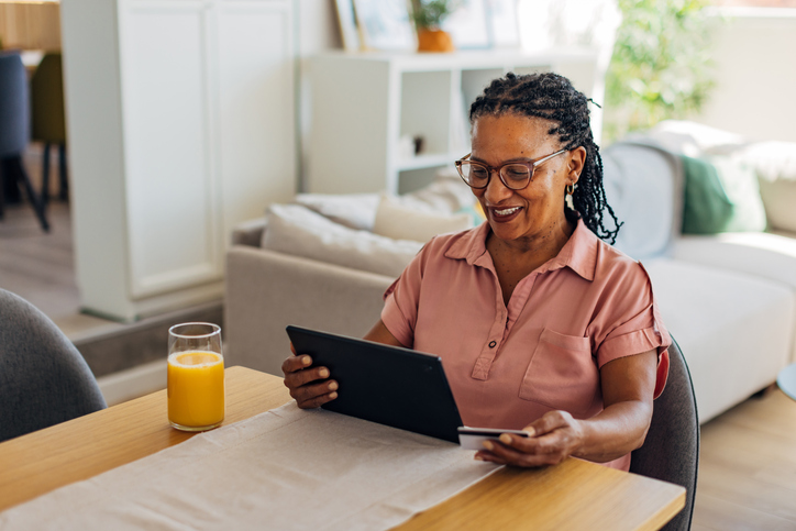 Smiling black woman checking credit card details to make contactless payment from home