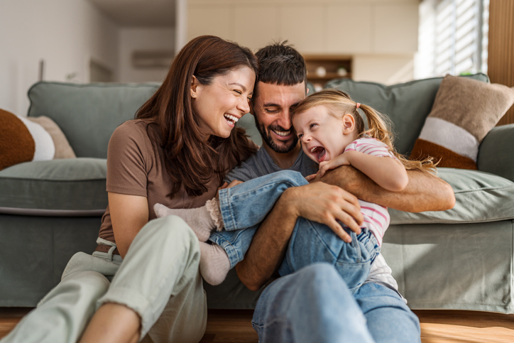 Cheerful parents playing with their young daughter, enjoying tickles and laughter, creating special family moments