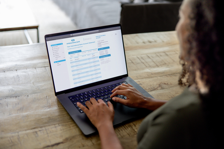 Woman at home checking her bank statement using a laptop Close-up on a woman at home checking her bank statement using a laptop - electronic banking concepts