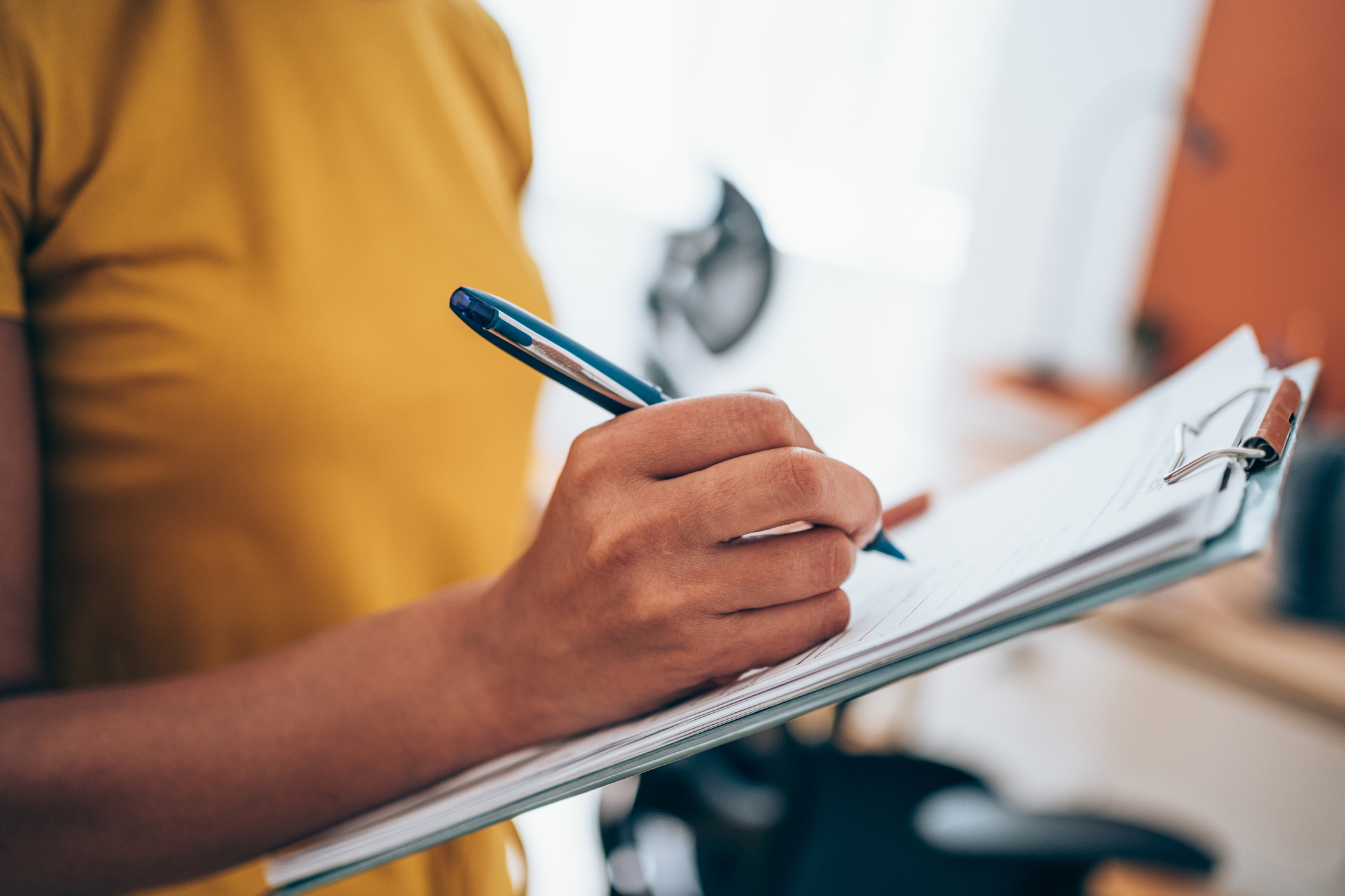 Woman hand writing on clipboard with a pen. Cropped shot of an unrecognizable businesswoman making notes on a clipboard inside of the office.